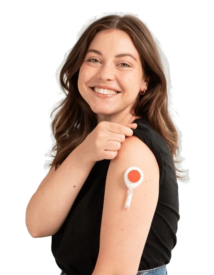 A woman with the Tasso+ device attached to her upper arm, smiling with her sleeve lifted.